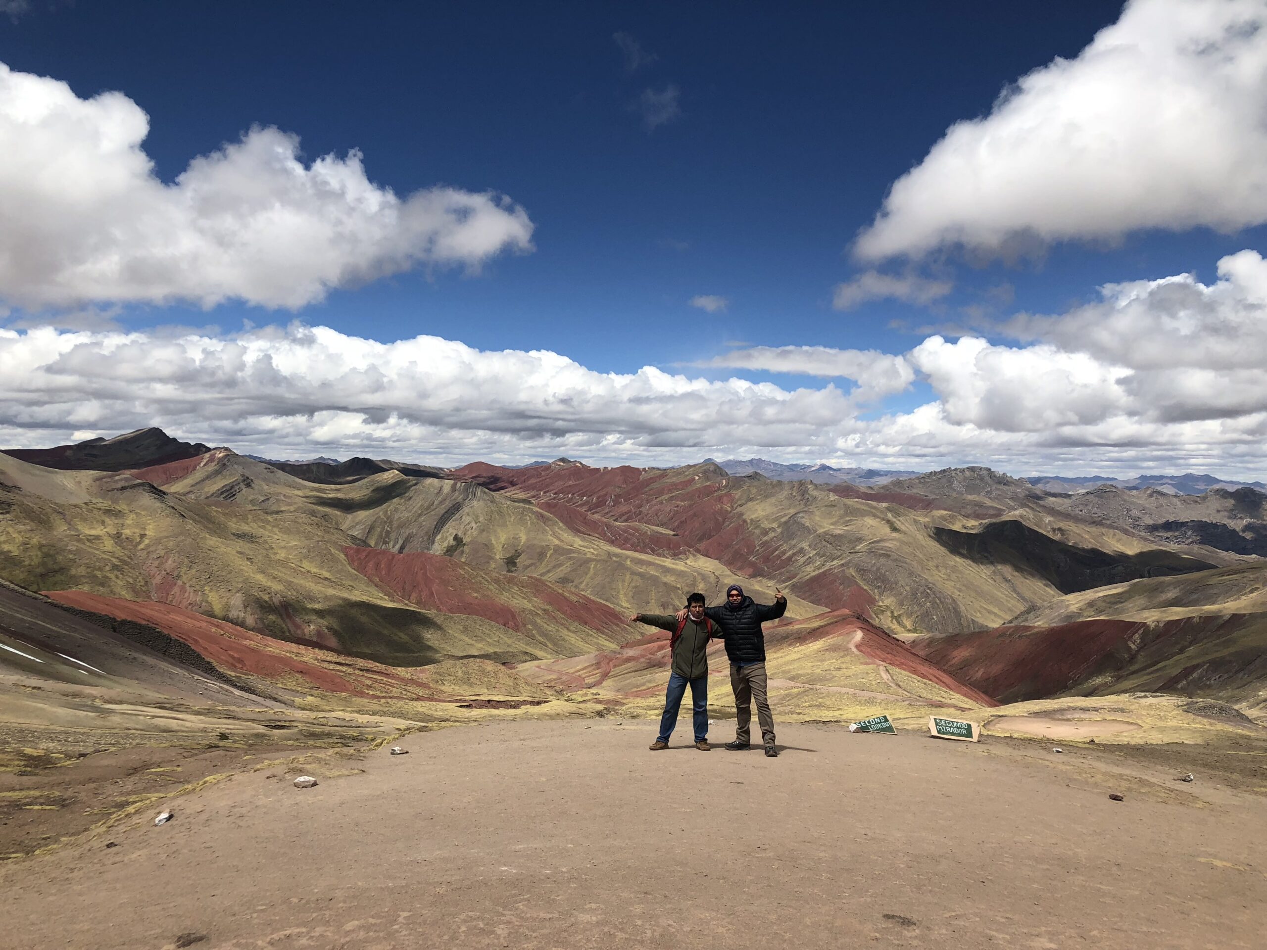 Travelers at the Second Lookout viewpoint overlooking Palcoyo's colored mountain ranges, an easier alternative to Rainbow Mountain