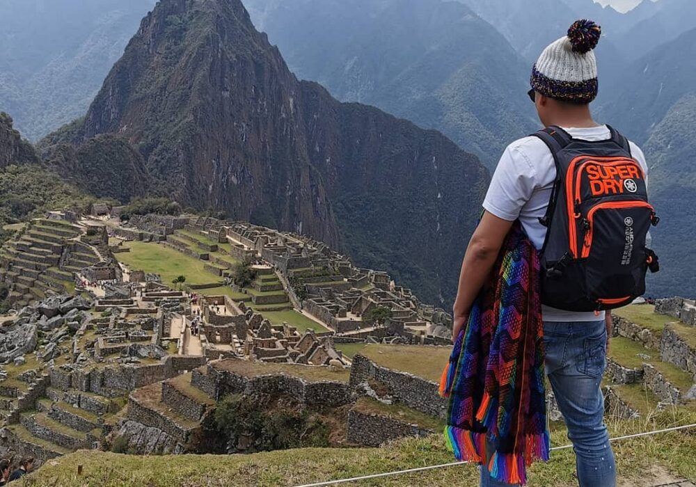 A traveler overlooking the Machu Picchu citadel and Huayna Picchu mountain, showcasing a successful arrival despite a Machu Picchu train cancelled scenario.