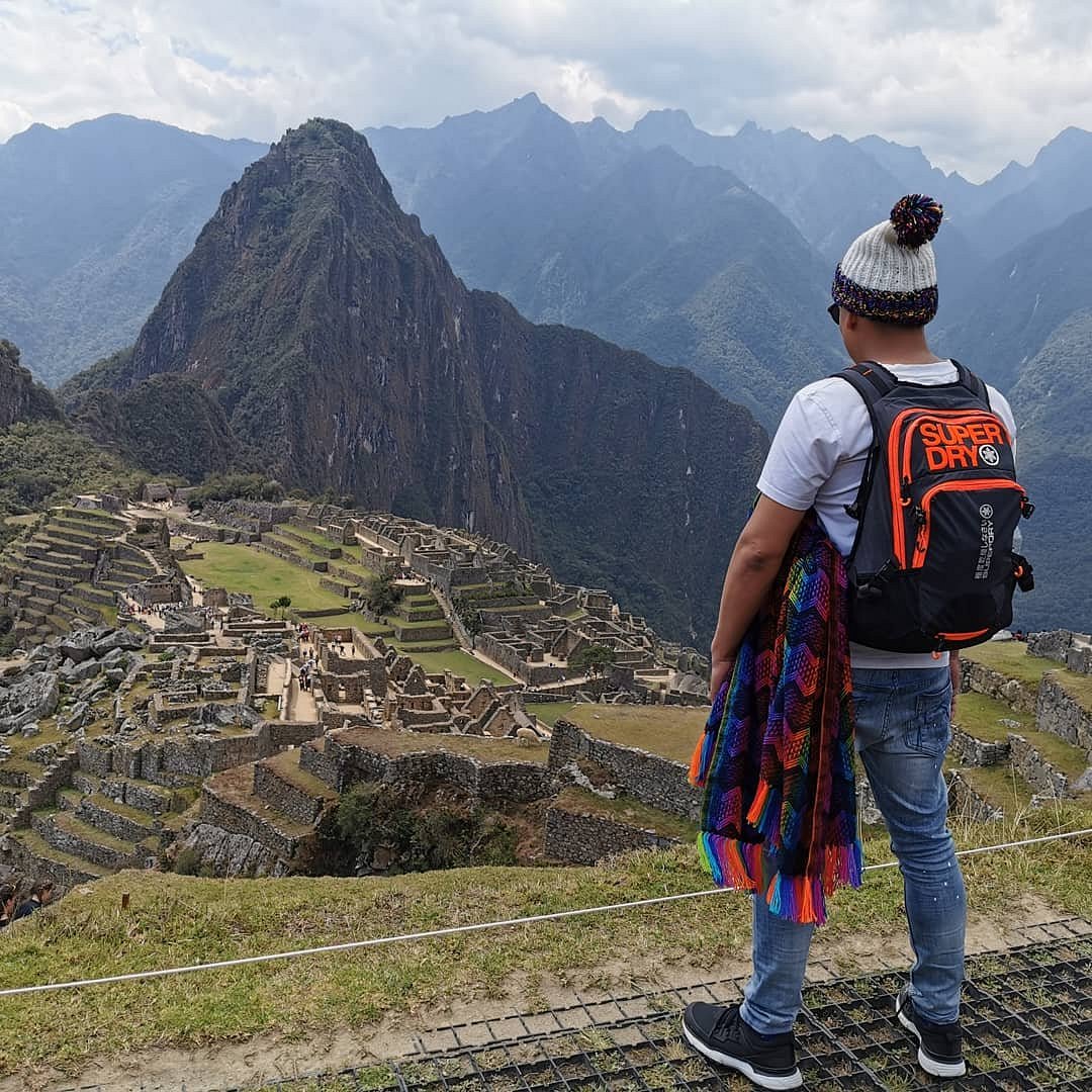 A traveler overlooking the Machu Picchu citadel and Huayna Picchu mountain, showcasing a successful arrival despite a Machu Picchu train cancelled scenario.