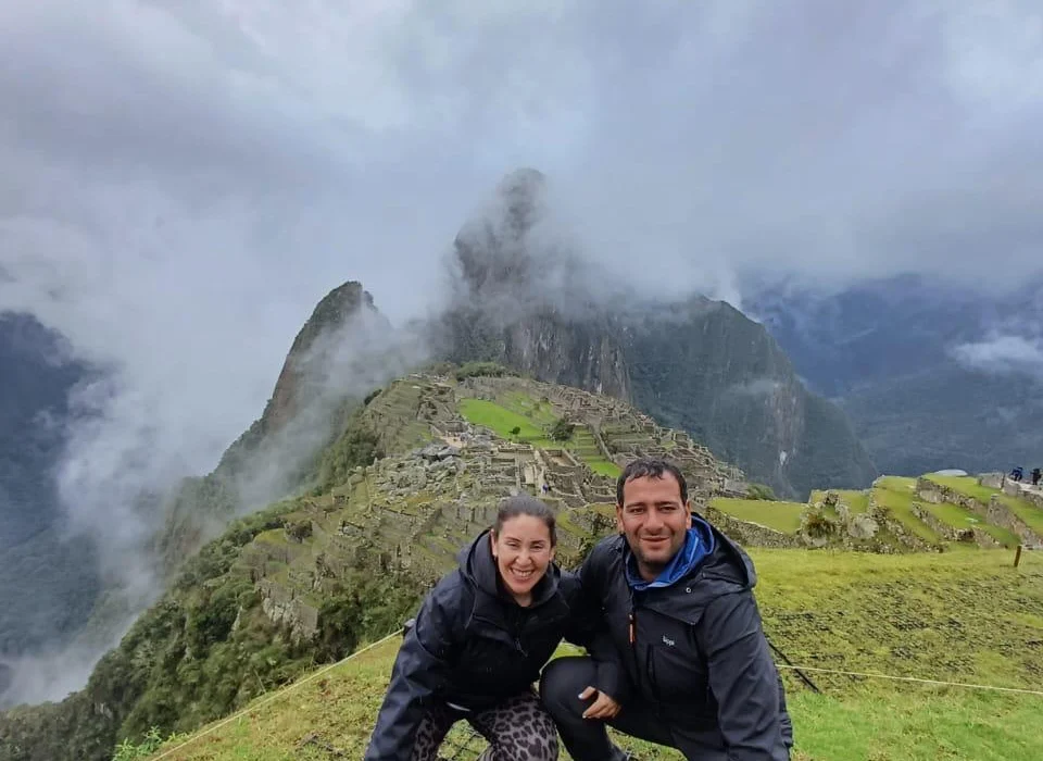 A smiling couple on a private guided tour at Machu Picchu, enjoying an exclusive view of the ruins without crowds.