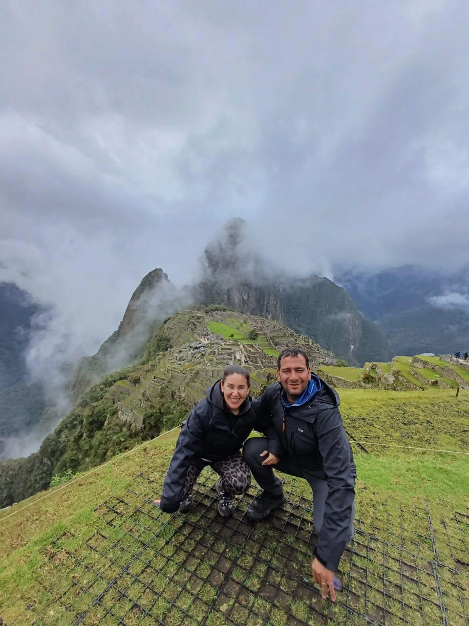 A smiling couple on a private guided tour at Machu Picchu, enjoying an exclusive view of the ruins without crowds.