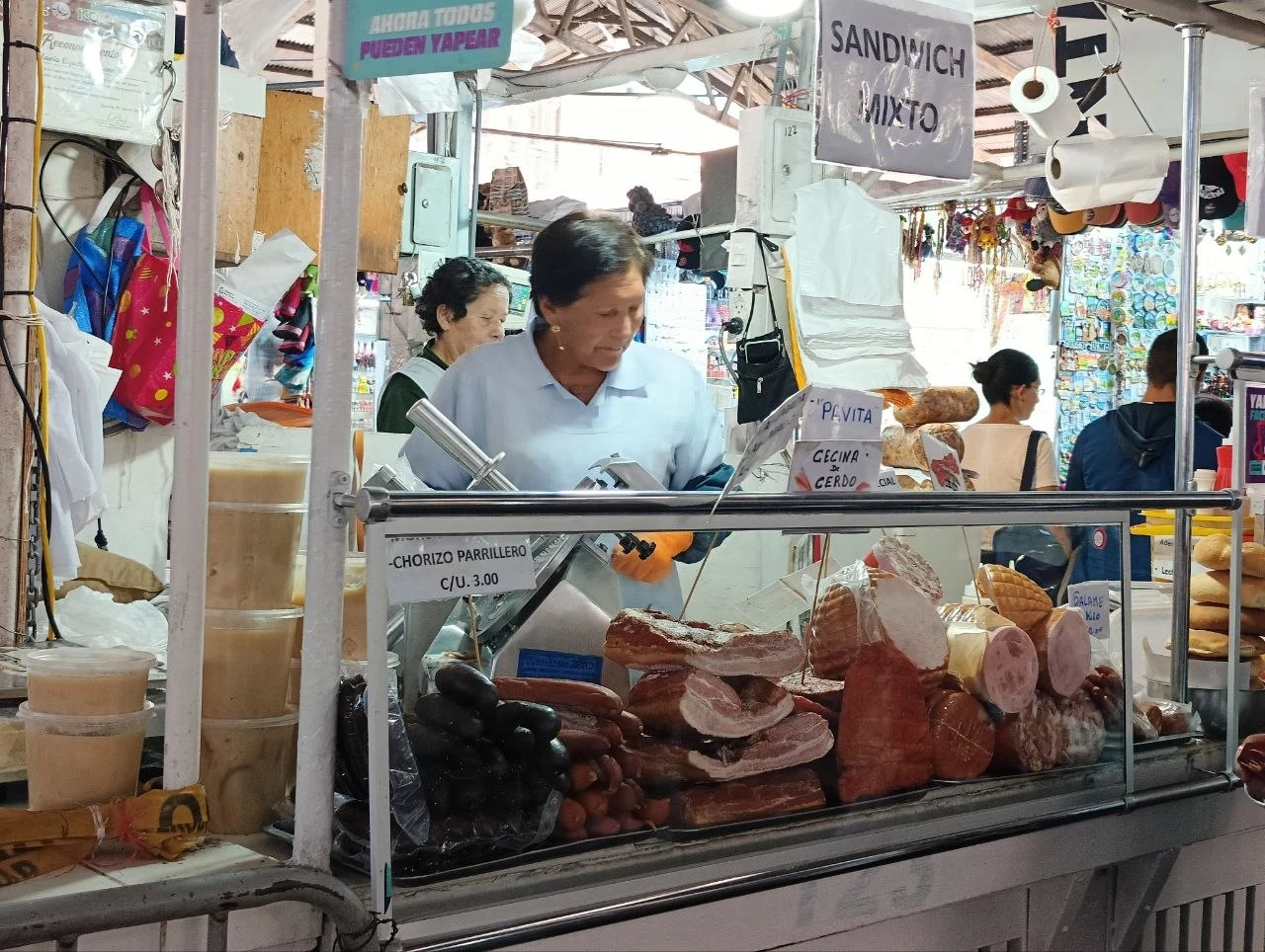 Traditional food in Cusco at Mercado San Pedro: a vendor slicing cured pork at a sandwich stall